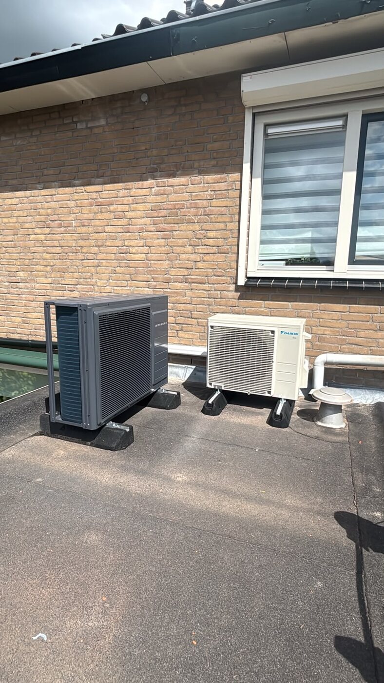 Buitenunits naast een bakstenen gebouw