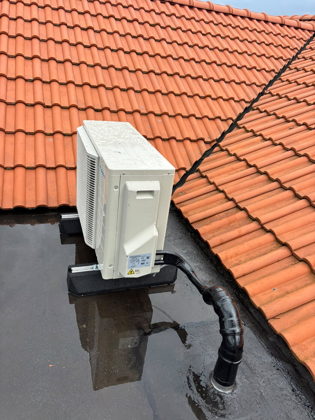 Buitenunit van een warmtepomp op een pannendak