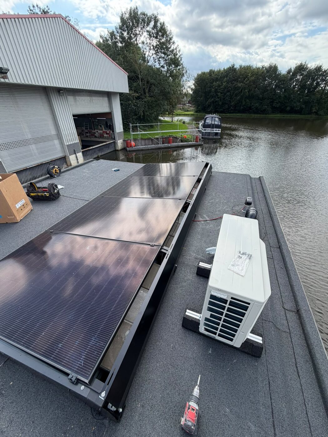 Zonnepanelen naast een warmtepomp op een plat dak